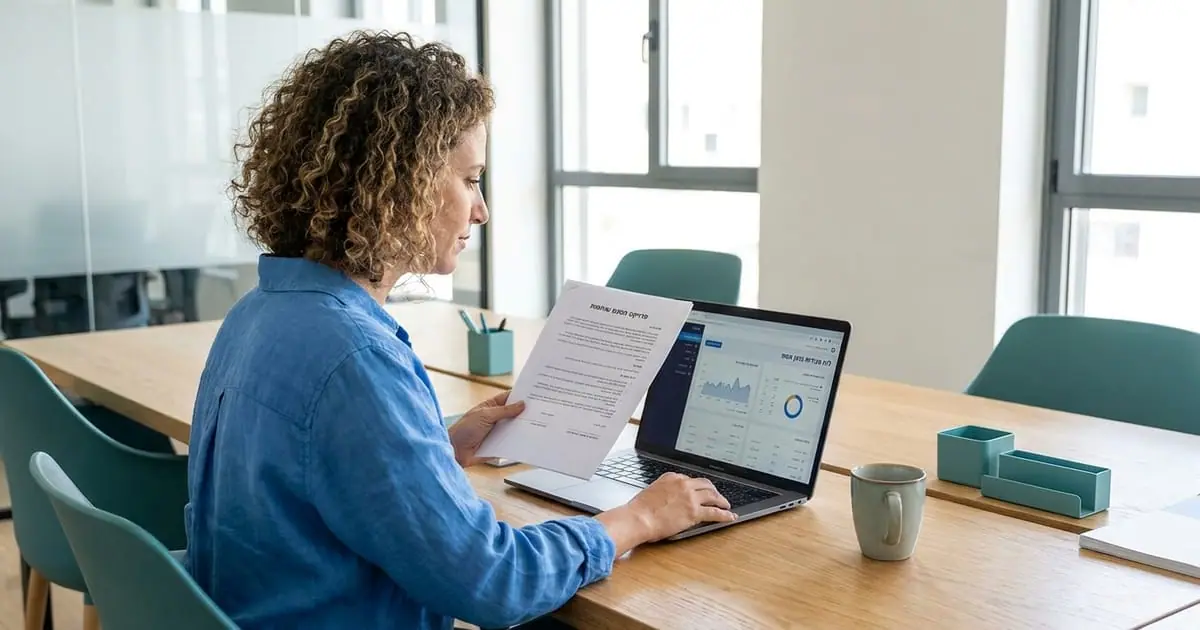 A business owner compares a printed project contract with a live sales dashboard on a laptop